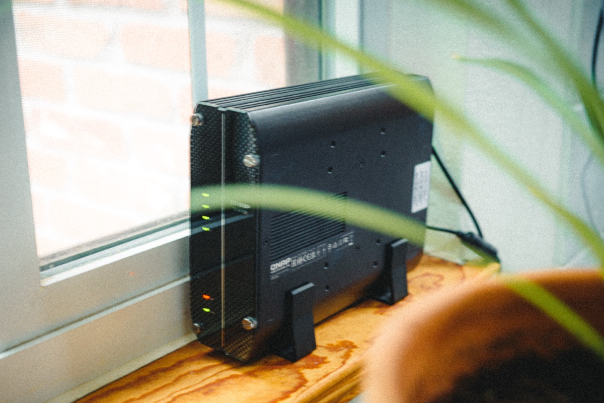 A QNAP NAS sitting on a windowsill beside a plant